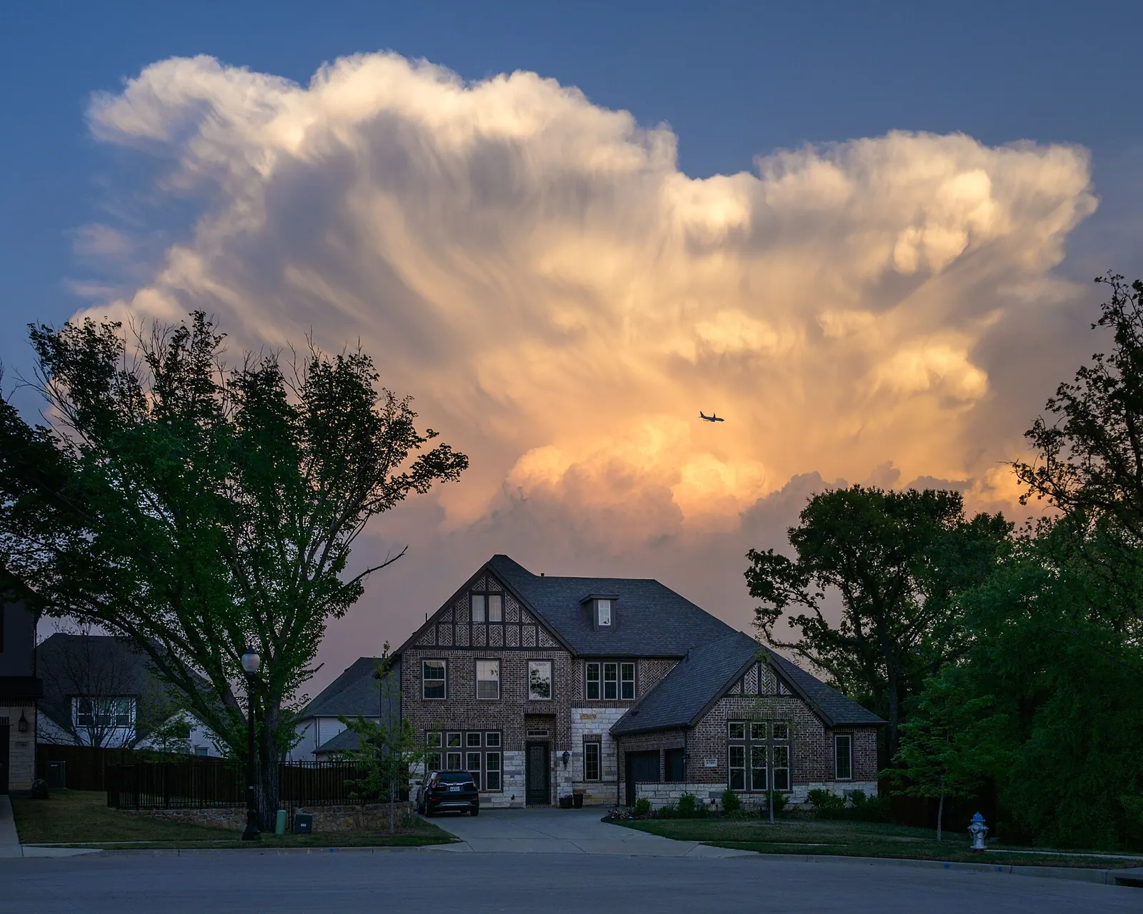 Brick and stone home under evening storm clouds in Flower Mound, Texas