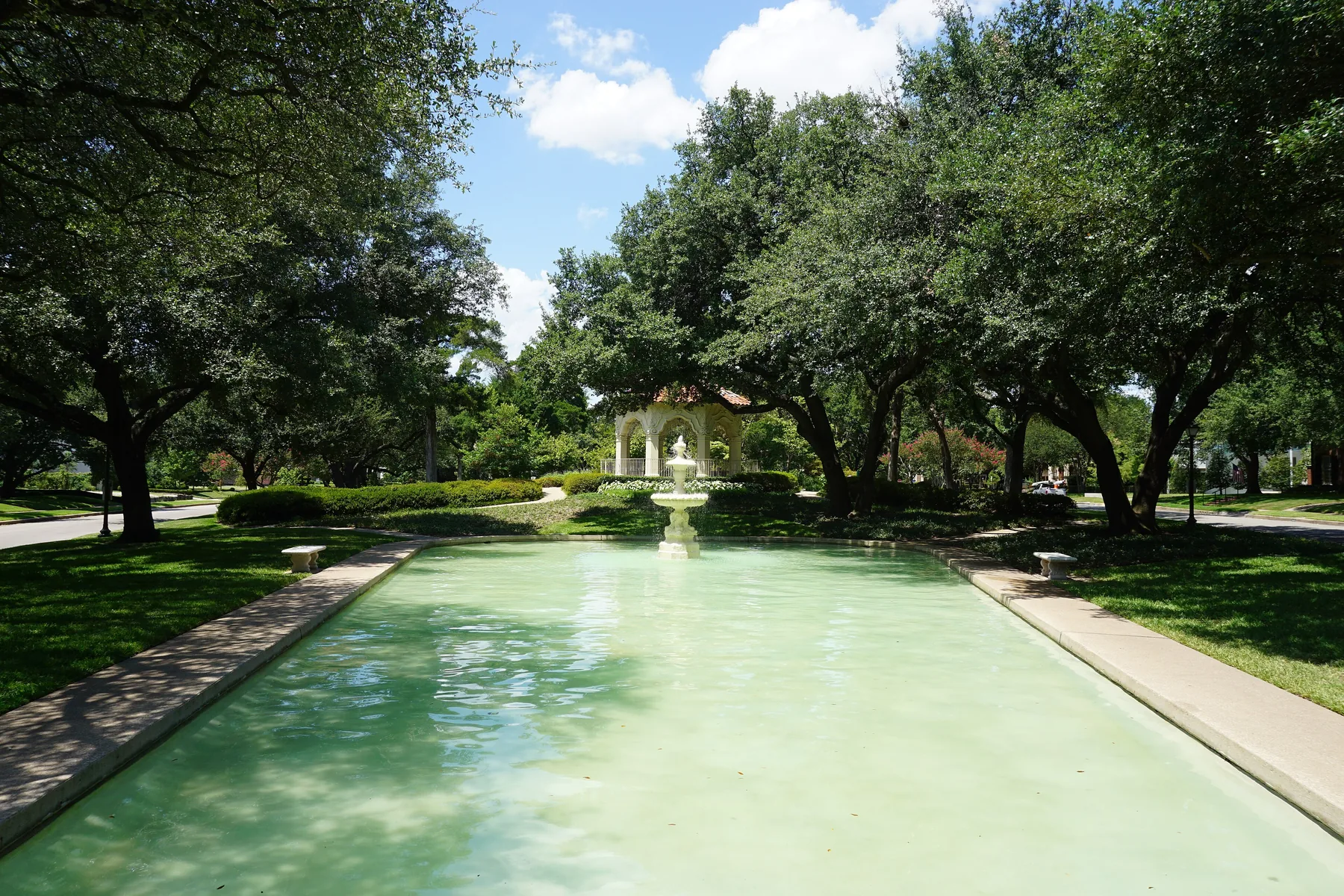 Reflecting pool and gazebo framed by live oaks at Flippen Park in Highland Park, Texas