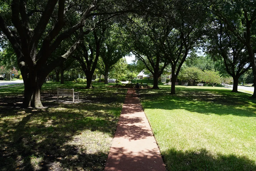 Brick path under a canopy of live oaks at Lockhart Park in Highland Park, Texas