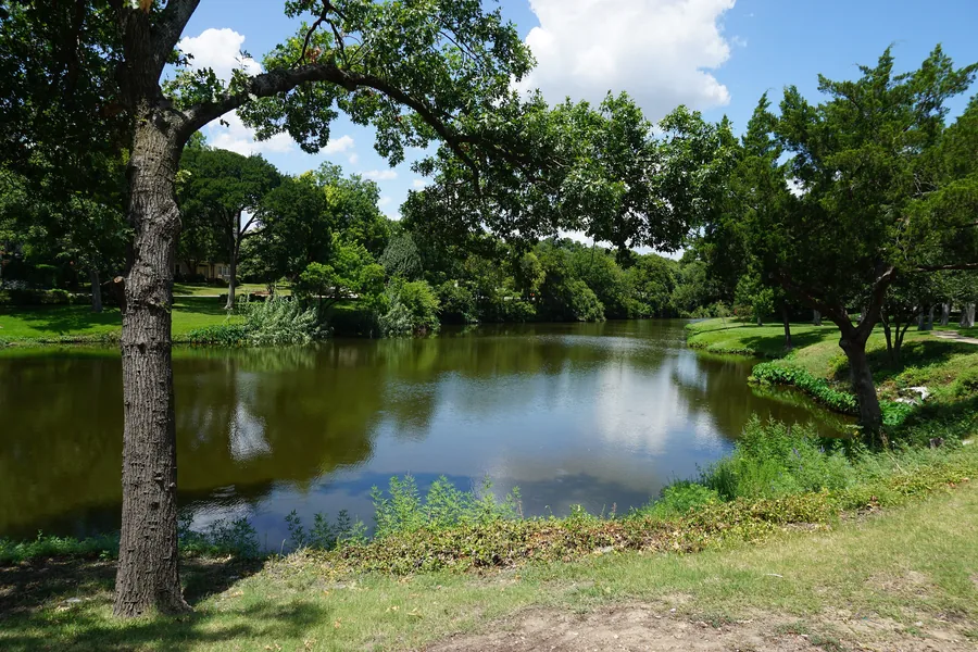 Pond and green lawns along Turtle Creek at Lakeside Park in Highland Park, Texas